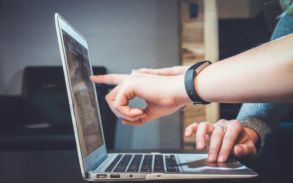 A person pointing at a laptop screen during a working session