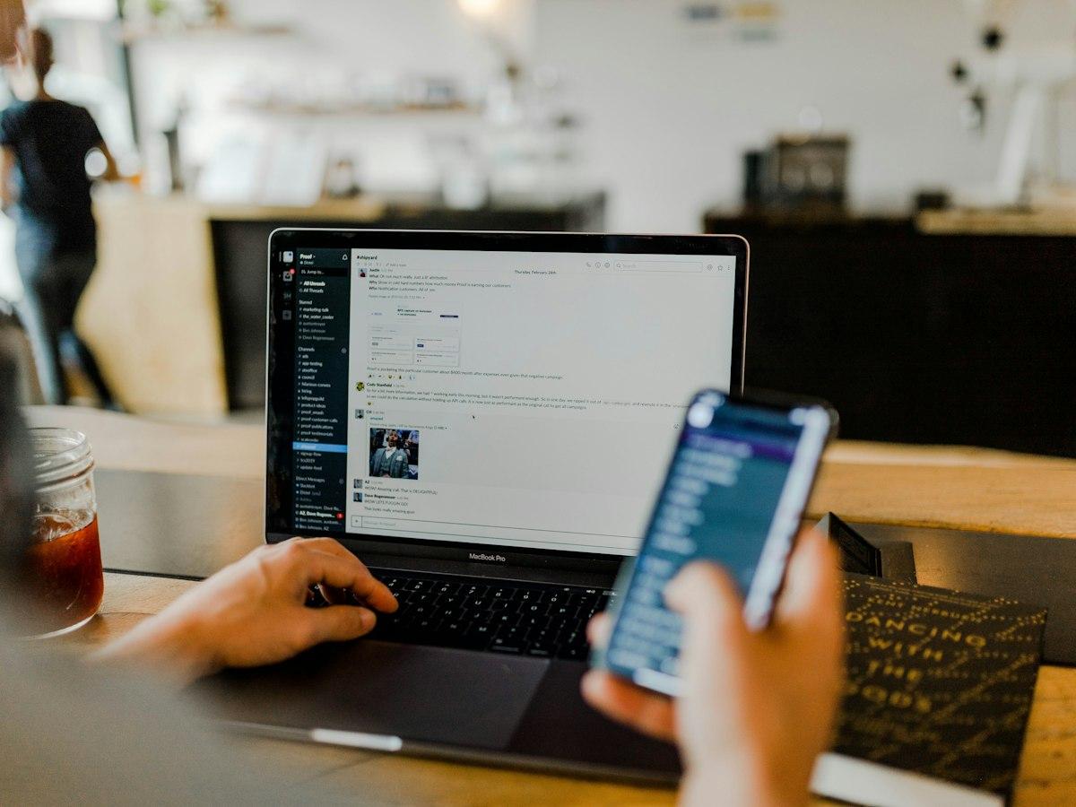 A person using a laptop and smartphone for business messaging